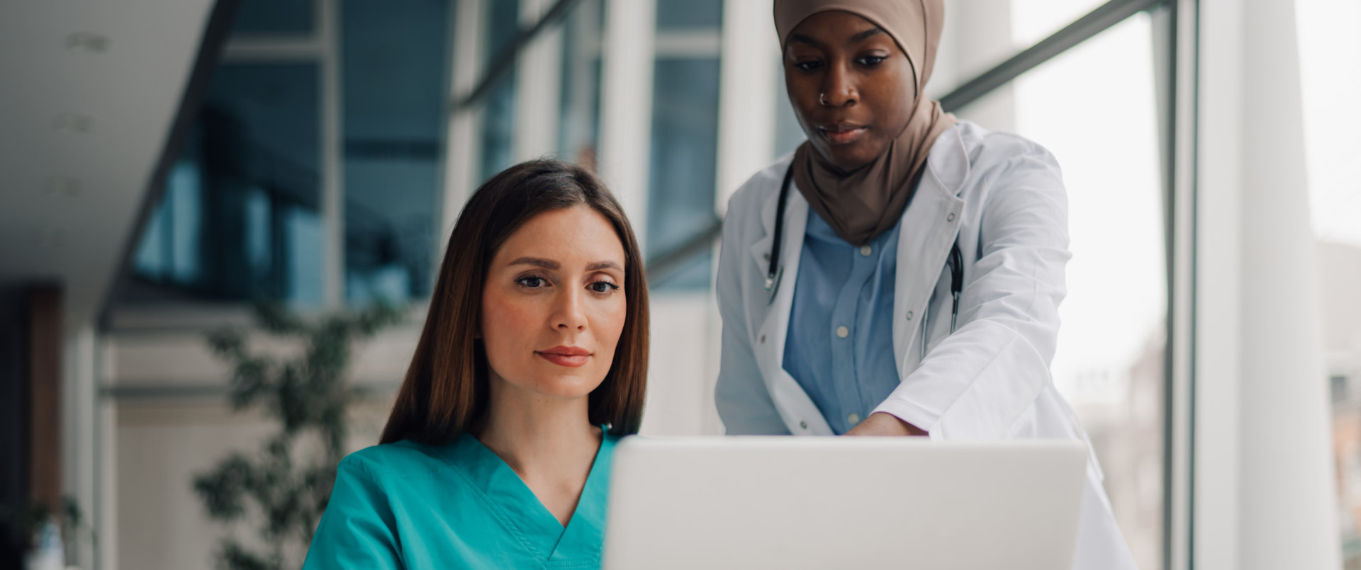 Two medical professionals are looking at a laptop computer