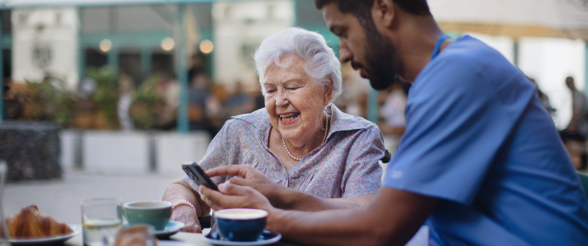  An older woman looks at a smartphone held by a man