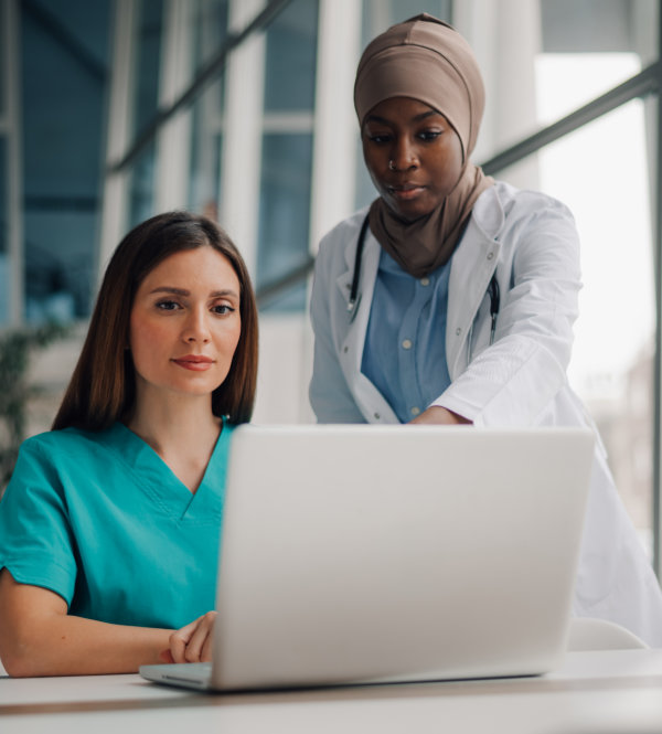 Two medical professionals are looking at a laptop computer