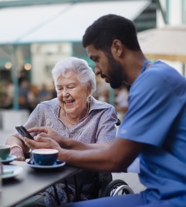  An older woman looks at a smartphone held by a man